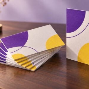 Fan of premium purple and yellow business cards on a walnut desk
